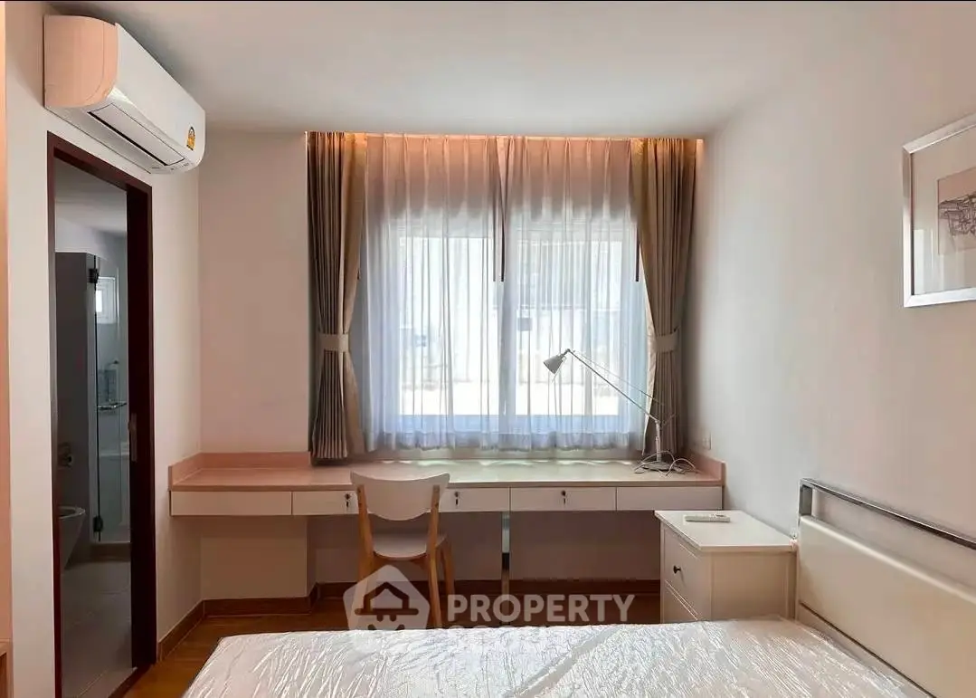 Bright bedroom with modern furniture and large window, perfect for a cozy and comfortable living space.