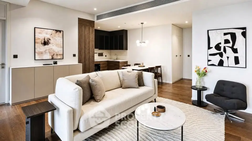 Modern living room with stylish decor and open kitchen layout, featuring elegant furniture and contemporary art.