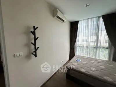 Modern bedroom with large window and air conditioning unit, featuring a minimalist design.