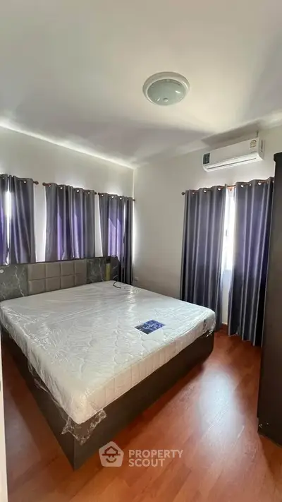Spacious bedroom with large windows and modern furnishings, perfect for comfortable living.