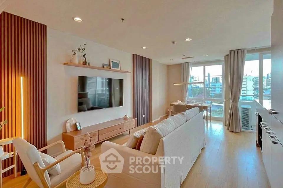 Spacious modern living room with large windows and stylish decor in a high-rise apartment.