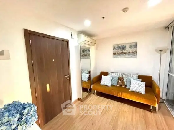 Cozy living room with stylish sofa and wall art, featuring wooden flooring and bright lighting.