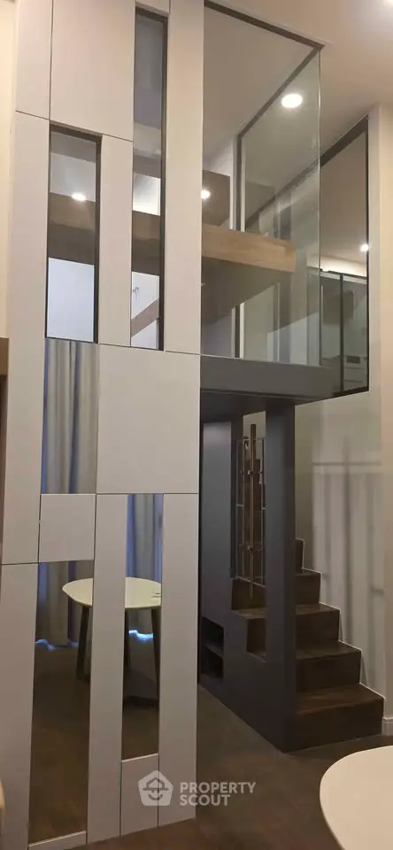 Modern duplex interior with stylish staircase and glass partitions, showcasing contemporary design and open space.