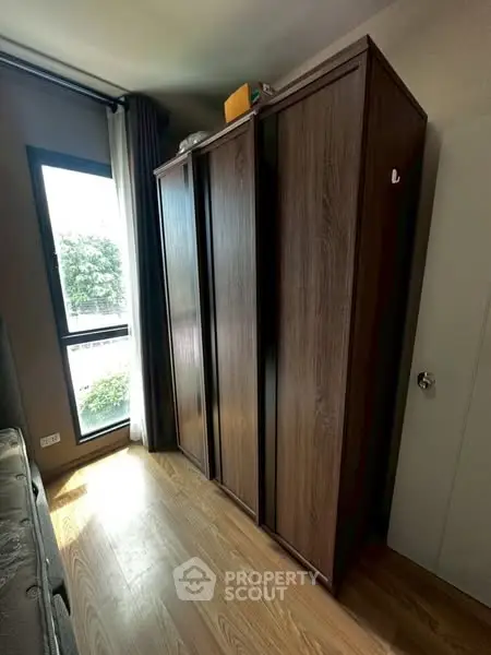 Spacious bedroom with large wooden wardrobe and natural light