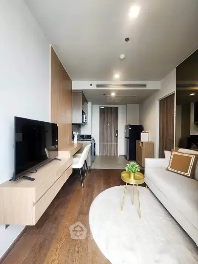 Modern living room with sleek furniture and open kitchen layout, featuring a stylish TV unit and cozy seating area.