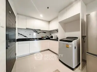 Modern kitchen with sleek white cabinets and washing machine