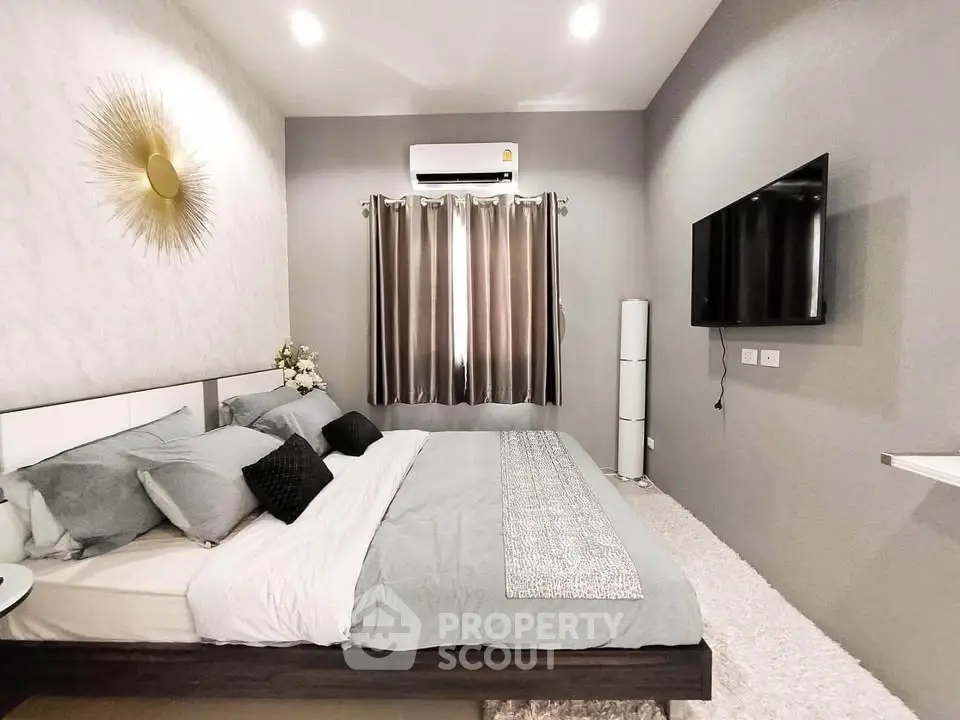 Modern bedroom with stylish decor and wall-mounted TV, featuring cozy bedding and ambient lighting.