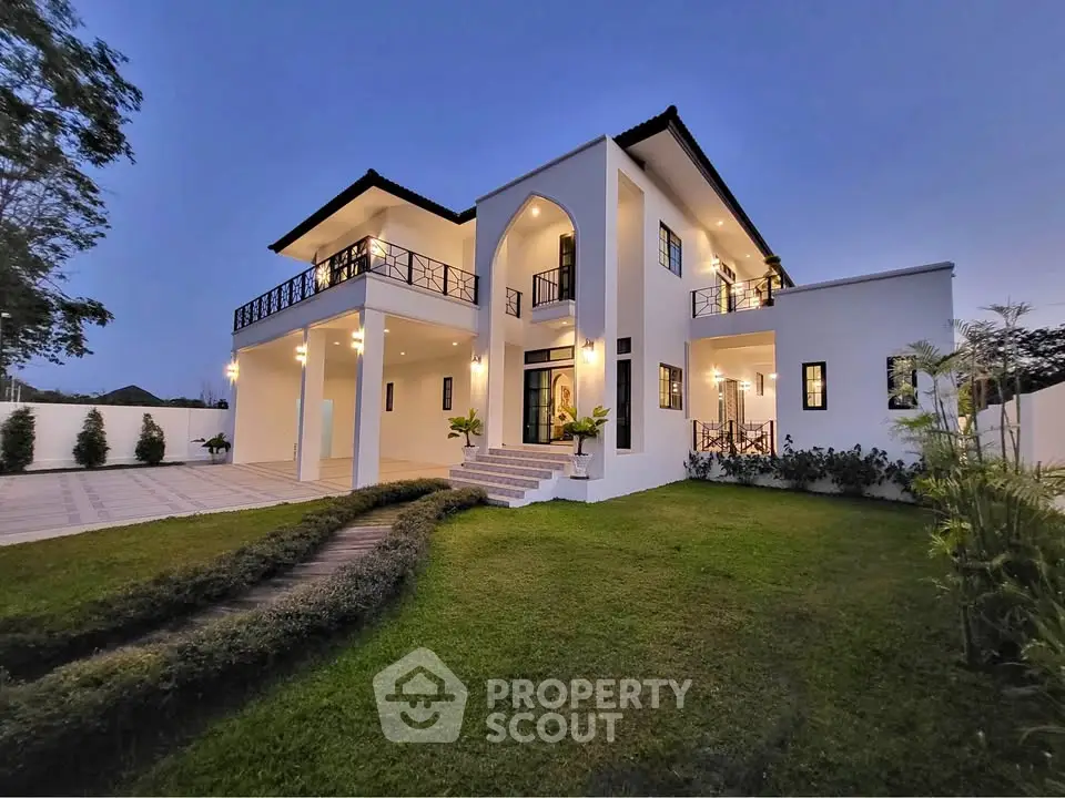Stunning modern two-story house with spacious balcony and lush green lawn at dusk.