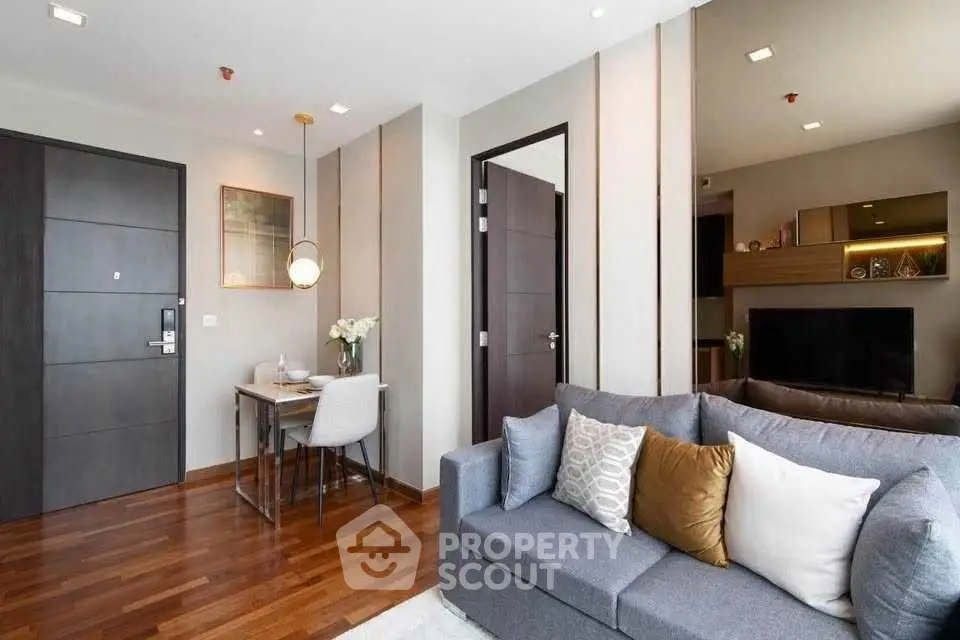 Modern living room with stylish decor and open dining area, featuring hardwood floors and contemporary furniture.
