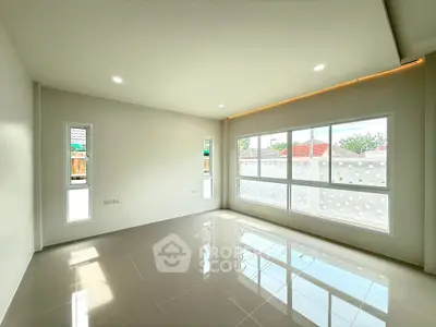 Spacious and bright living room with large windows and modern tile flooring