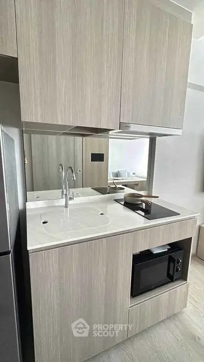 Modern compact kitchen with sleek cabinetry and built-in appliances in a stylish apartment.