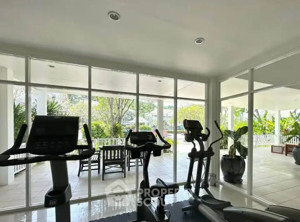 Modern gym with cardio equipment and garden view in luxury real estate property.