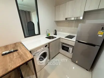 Modern compact kitchen with washing machine and sleek appliances in stylish apartment.