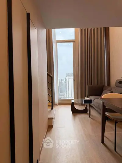 Modern living room with floor-to-ceiling windows and city view, featuring stylish furniture and wooden flooring.