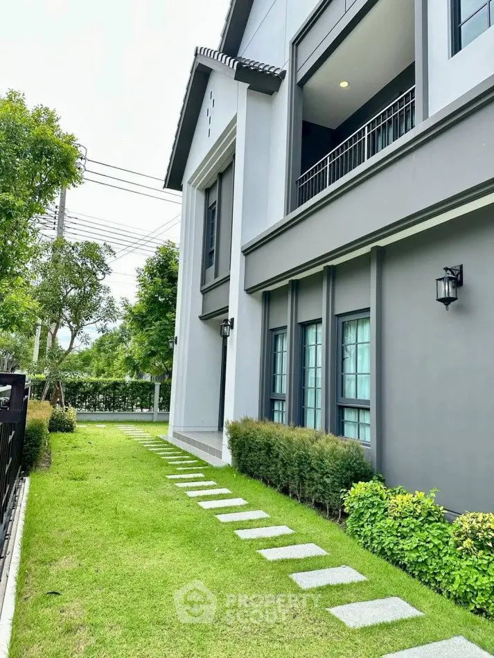 Modern two-story house with lush green garden and stylish exterior design.