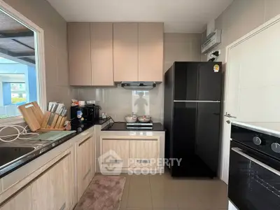 Modern kitchen with sleek cabinetry, black fridge, and built-in oven in a stylish home.