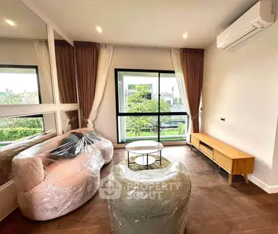 Modern living room with large window and air conditioning, featuring stylish furniture and garden view.