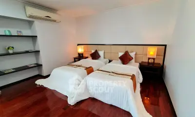 Elegant twin bedroom with modern decor and wooden flooring, perfect for a cozy stay.