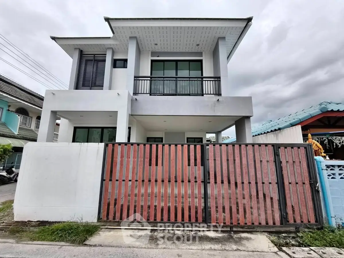 Modern two-story house with a sleek design and gated entrance.