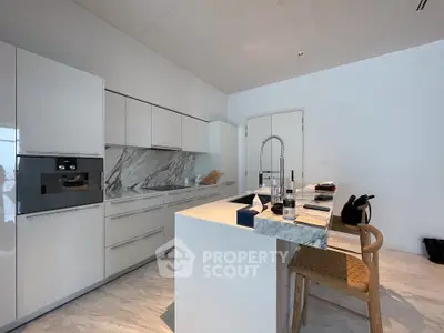Modern kitchen with sleek white cabinets and marble accents, featuring a stylish island and high-end appliances.