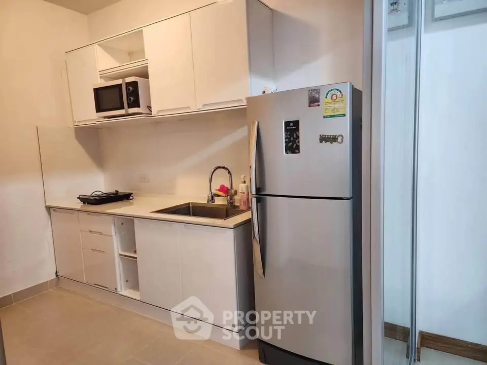 Modern kitchen with sleek white cabinets and stainless steel appliances in a compact layout.