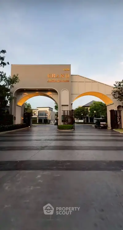 Elegant entrance of a luxury residential complex with grand archway and modern design.