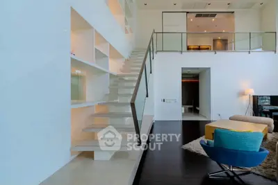 Luxurious modern living room with open staircase and stylish furniture in a high-ceiling apartment.