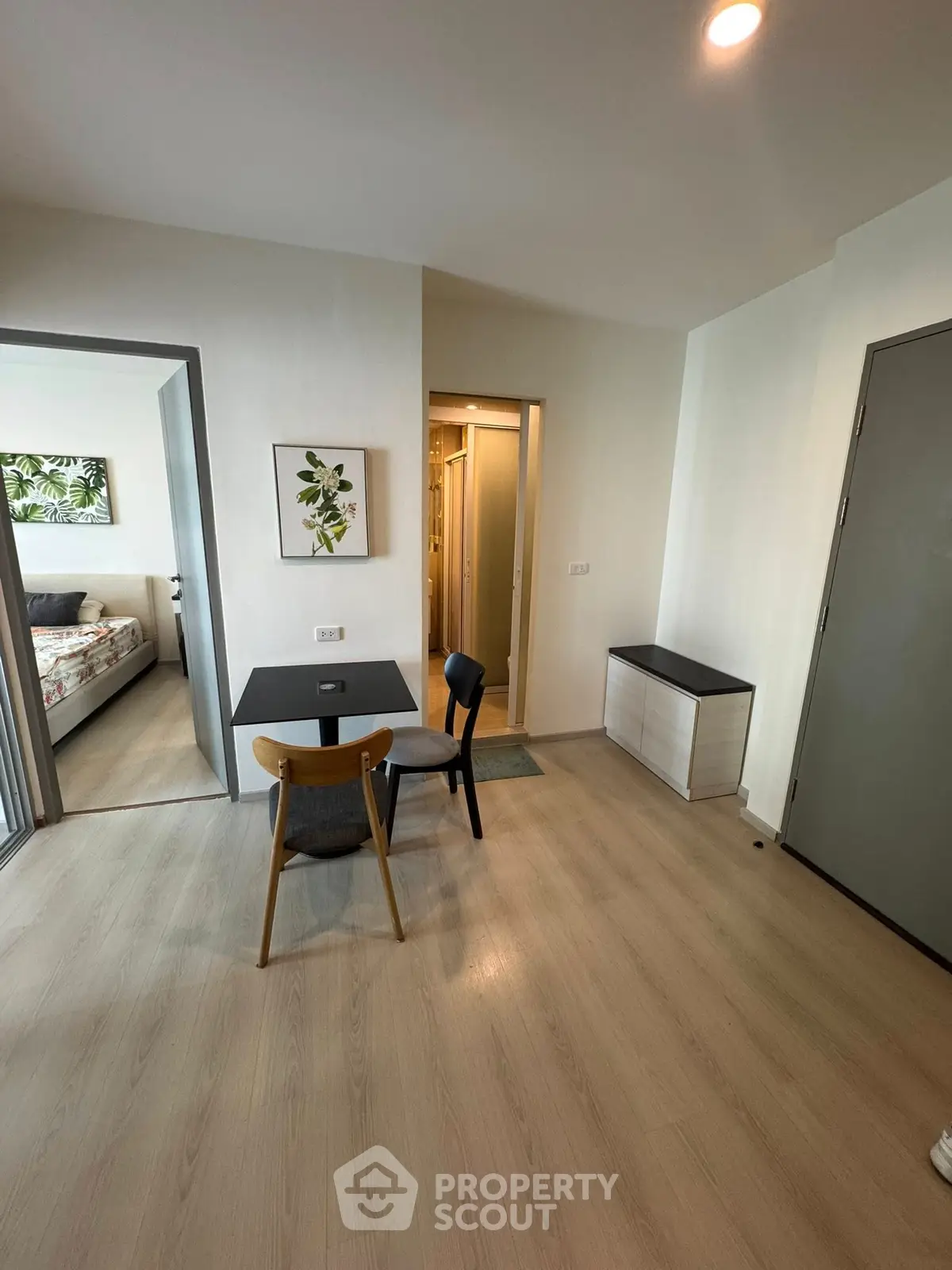 Modern apartment interior with dining area and bedroom view, featuring stylish decor and wooden flooring.