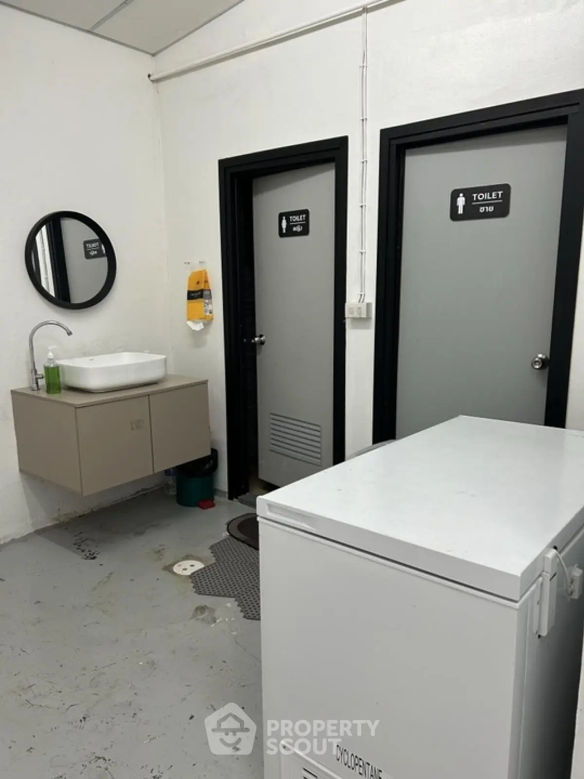 Commercial restroom with two toilet doors, sink, and storage unit
