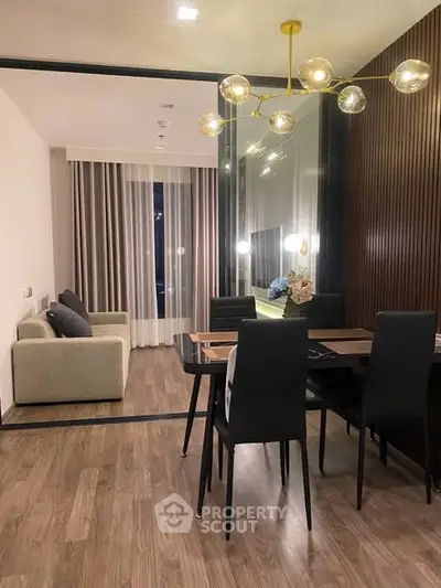 Modern dining area with elegant lighting and cozy living room in open layout apartment.