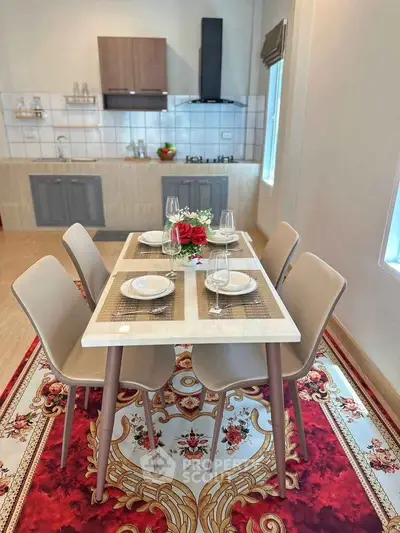 Stylish dining area with elegant table setting and modern kitchen in background.