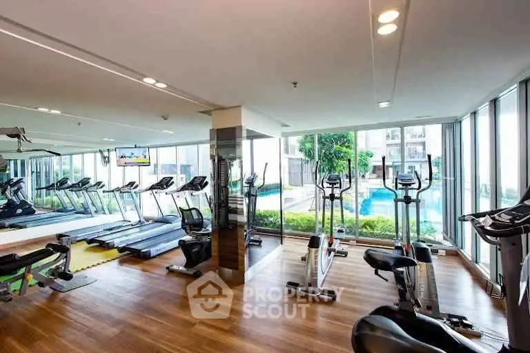 Luxurious gym with modern equipment and pool view in upscale residential complex.