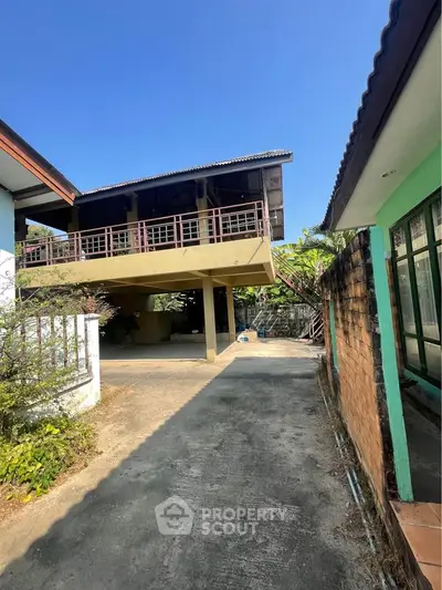 Charming elevated home with spacious driveway and lush greenery, perfect for serene living.