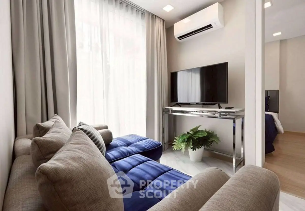 Modern living room with plush sofa, large TV, and elegant decor in a bright, airy space.