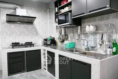 Modern kitchen with sleek black cabinets and dual sinks, featuring a gas stove and ample storage.