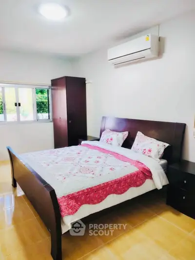 Cozy bedroom with modern furniture and air conditioning, featuring a large window for natural light.