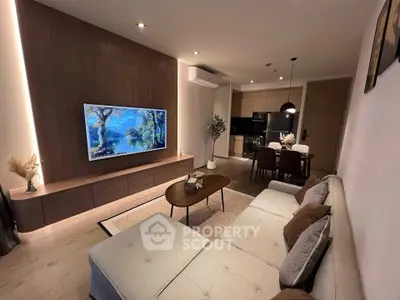 Modern living room with open kitchen, featuring stylish furniture and ambient lighting.