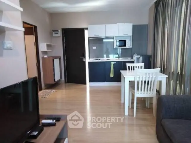 Modern open-plan living room with kitchen and dining area, featuring sleek furniture and natural light.