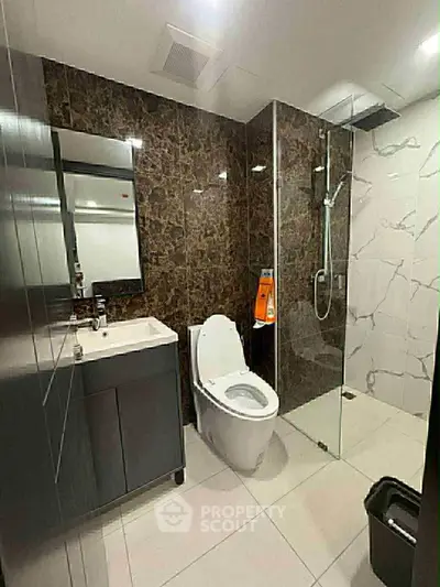 Modern bathroom with glass shower and marble accent wall
