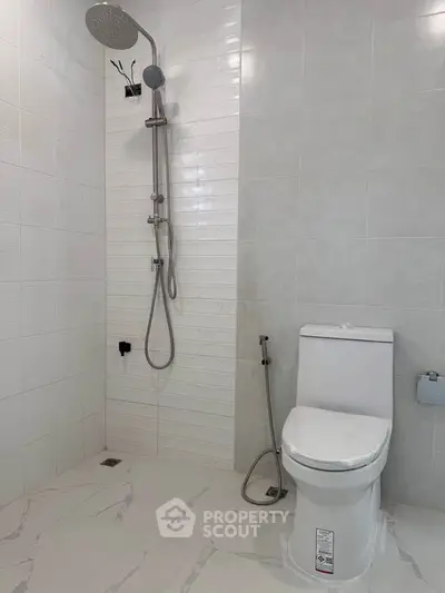 Modern bathroom with sleek shower and toilet in minimalist design.