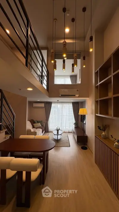 Modern duplex living room with high ceiling and stylish lighting, featuring cozy seating and elegant decor.