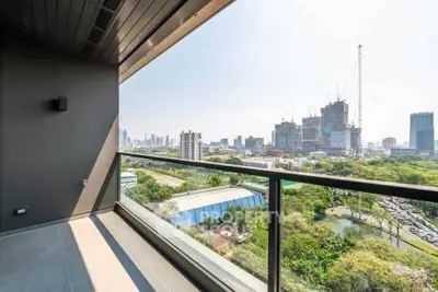 Stunning balcony view of city skyline and lush greenery in modern high-rise apartment.
