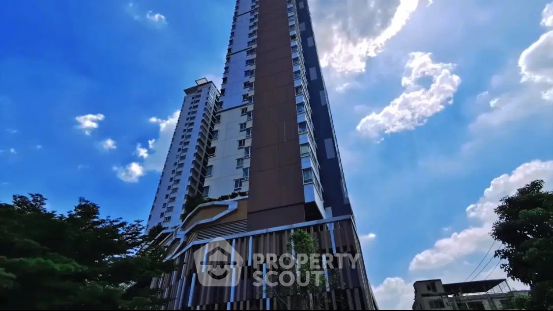 Stunning skyscraper against a vibrant sky with lush greenery, perfect for urban living.