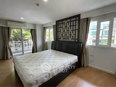 Spacious bedroom with large windows and balcony access in modern apartment