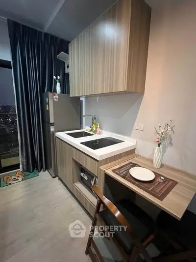Modern compact kitchen with sleek wooden cabinets and city view, perfect for urban living.