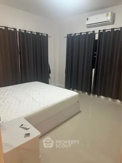 Modern bedroom with sleek design and air conditioning, featuring dark curtains and a comfortable bed.