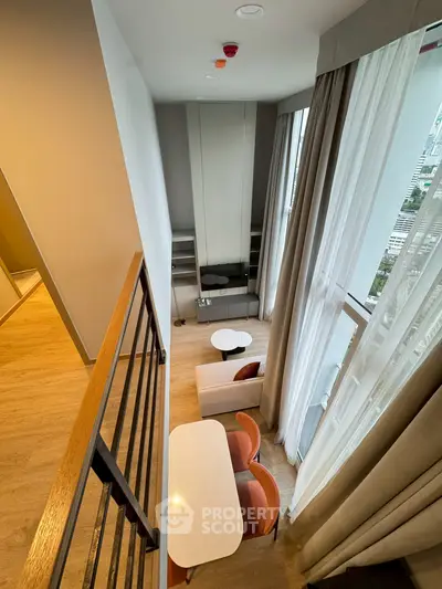 Modern loft-style living room with high ceilings and large windows offering city views.