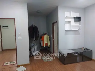 Spacious living area with modern decor and wooden flooring, featuring a stylish wall shelf and ample natural light.