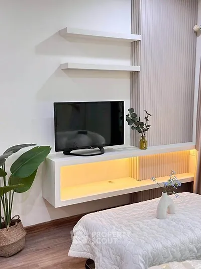 Modern bedroom with sleek TV setup and stylish decor, featuring elegant lighting and contemporary design.