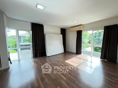 Spacious unfurnished room with large windows and wooden flooring, perfect for customization.